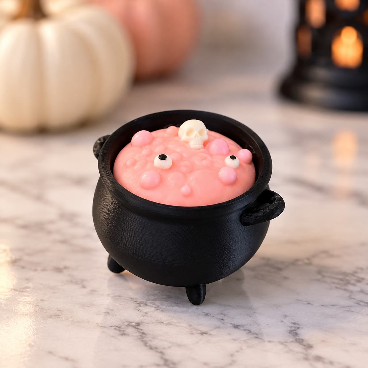 3D printed black cauldron clicker with pink bubbling potion and skull